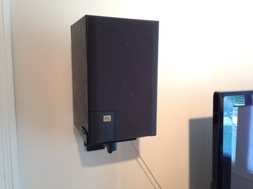 JBL J520m speaker wall mounted with grill cover next to TV