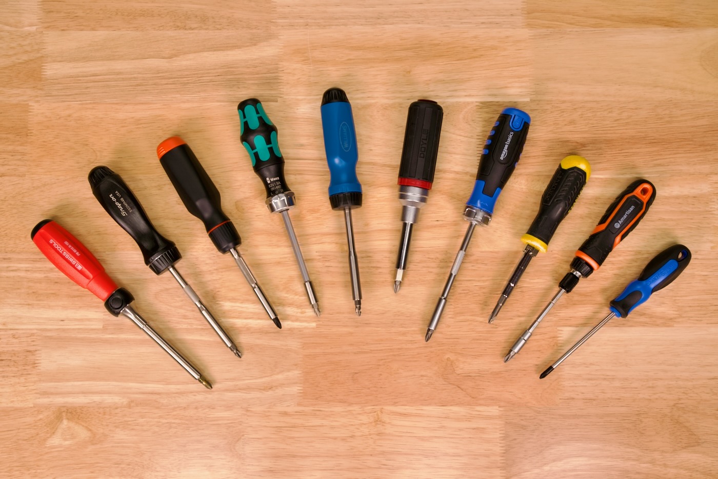 All ratcheting screwdrivers under test laid out on wooden workbench