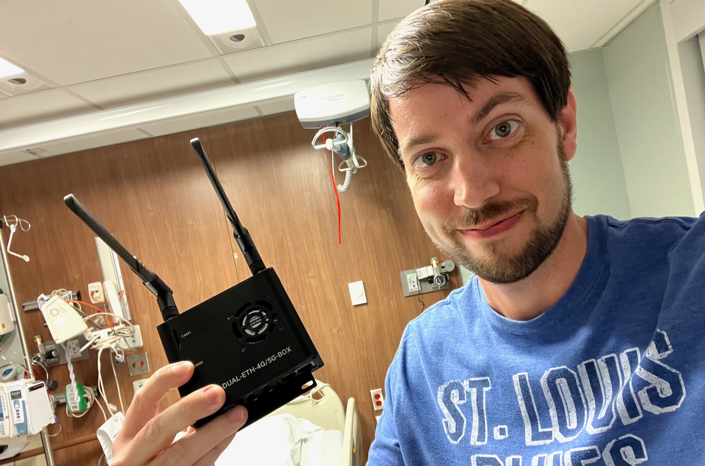 Jeff Geerling holding 4G LTE Raspberry Pi Waveshare Dual Ethernet Router in hospital room