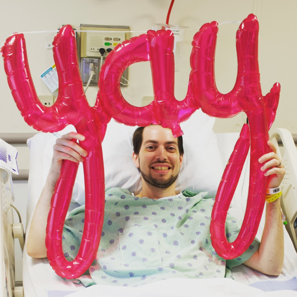Jeff Geerling holding yay sign in hospital bed after surgery